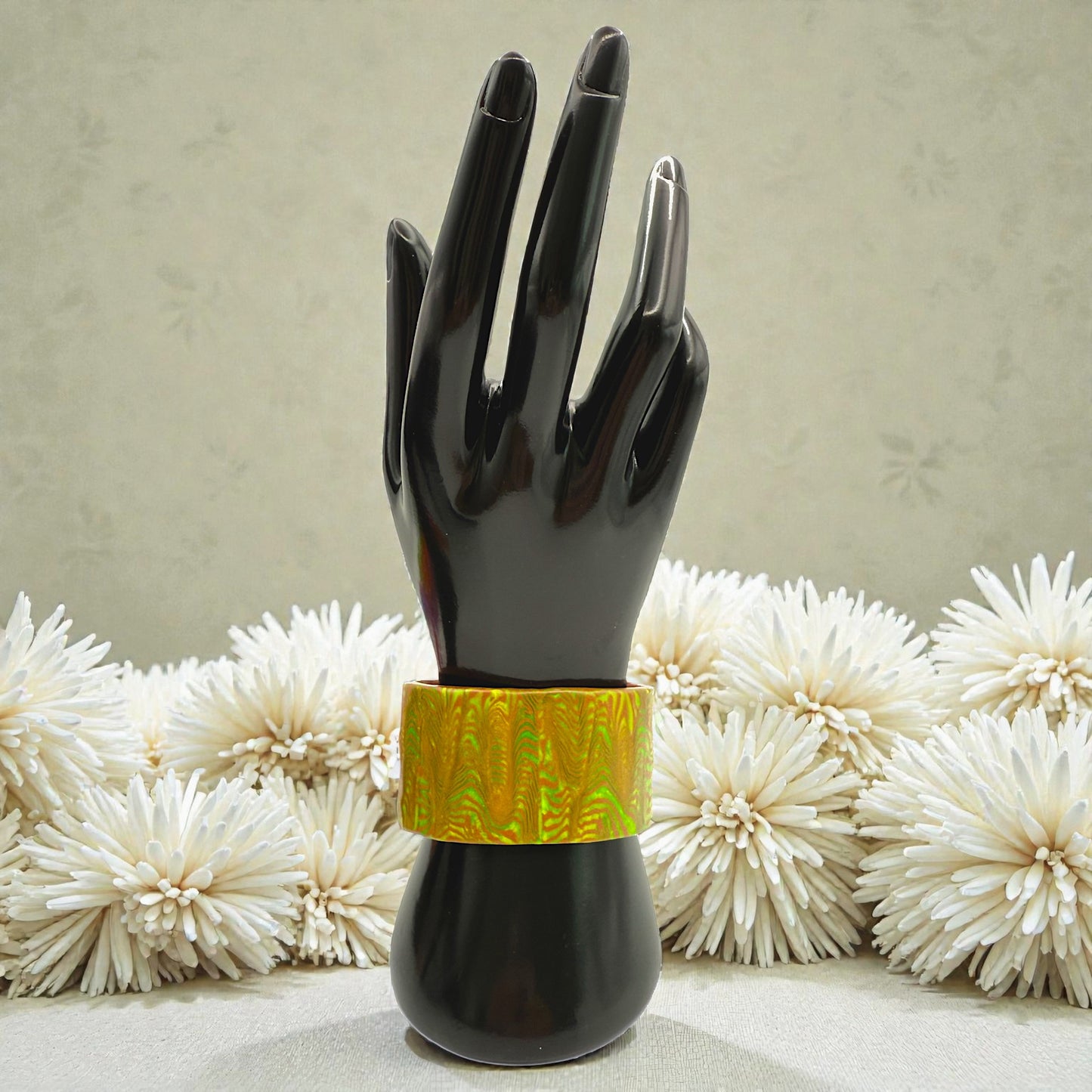 These Pretty Things Chocolate Lime Cuff on a black hand mannequin with a cream colour feather boa in the background