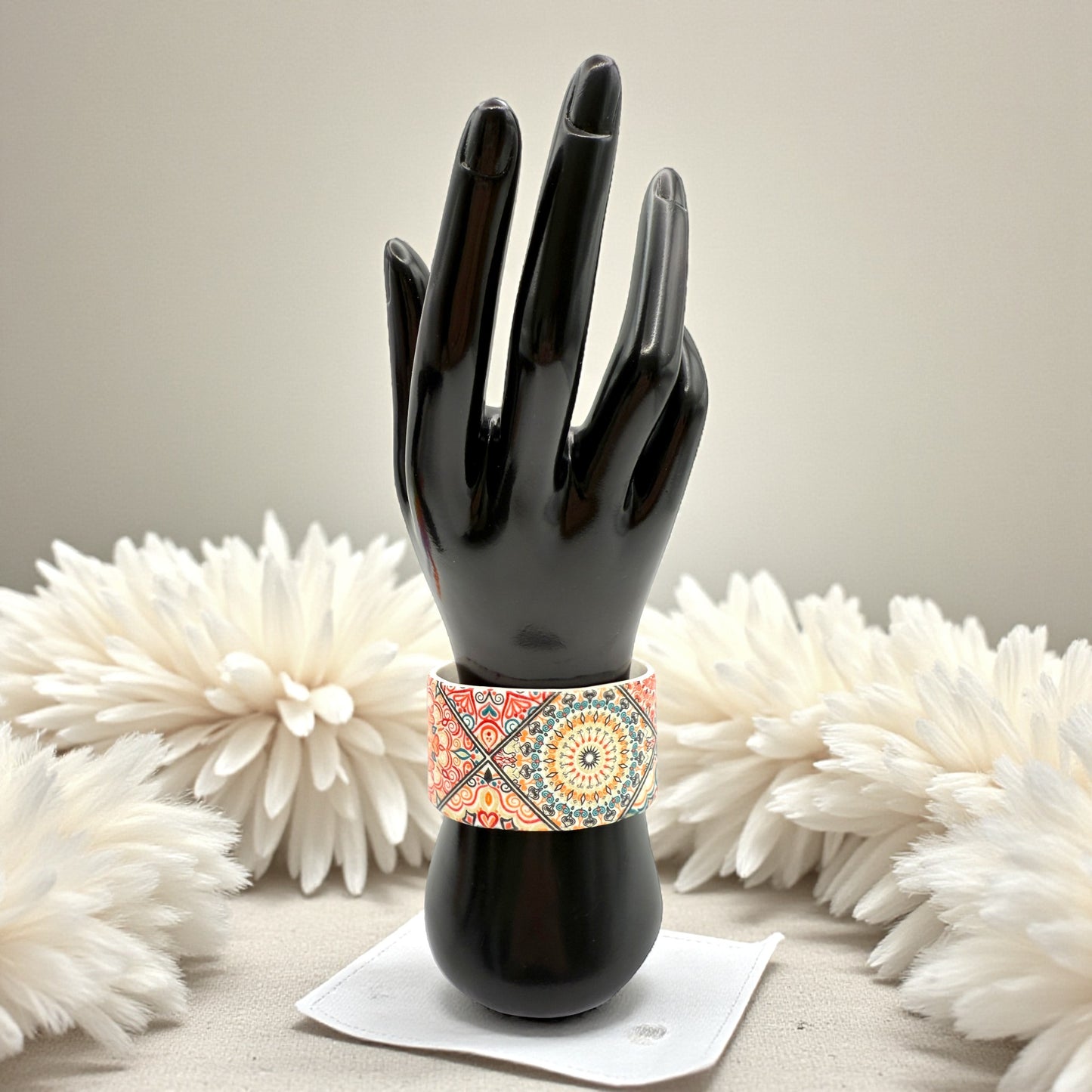 These Pretty Things Jaipur Cuff on a black hand/wrist mannequin which is within a white colour feather boa