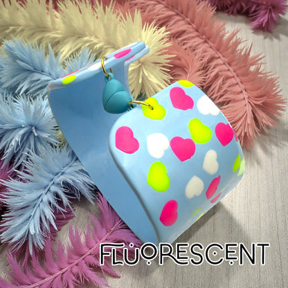 These Pretty Things Blue Fluorescent Cuff on a wood table with various pale coloured feather boas in the background