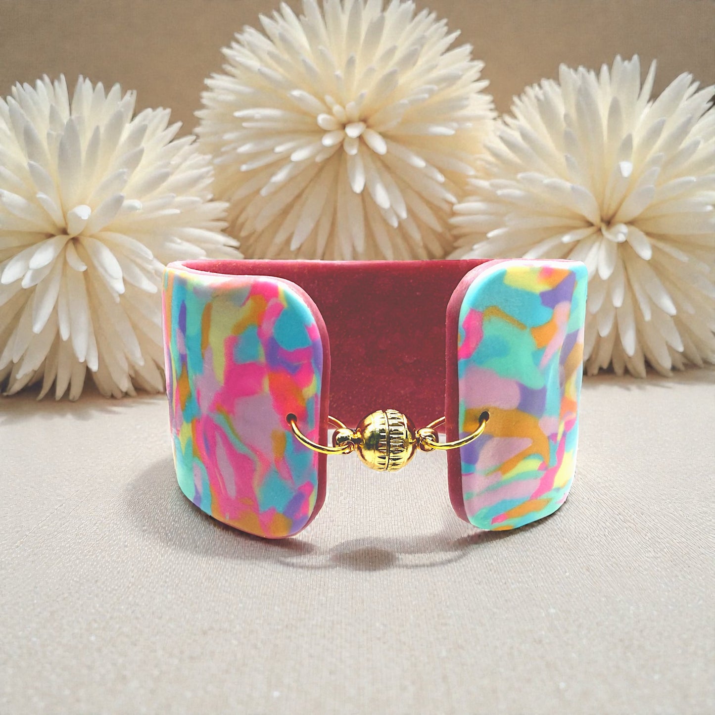These Pretty Things Candy Cane Cuff on a table with a cream feather boa in the background