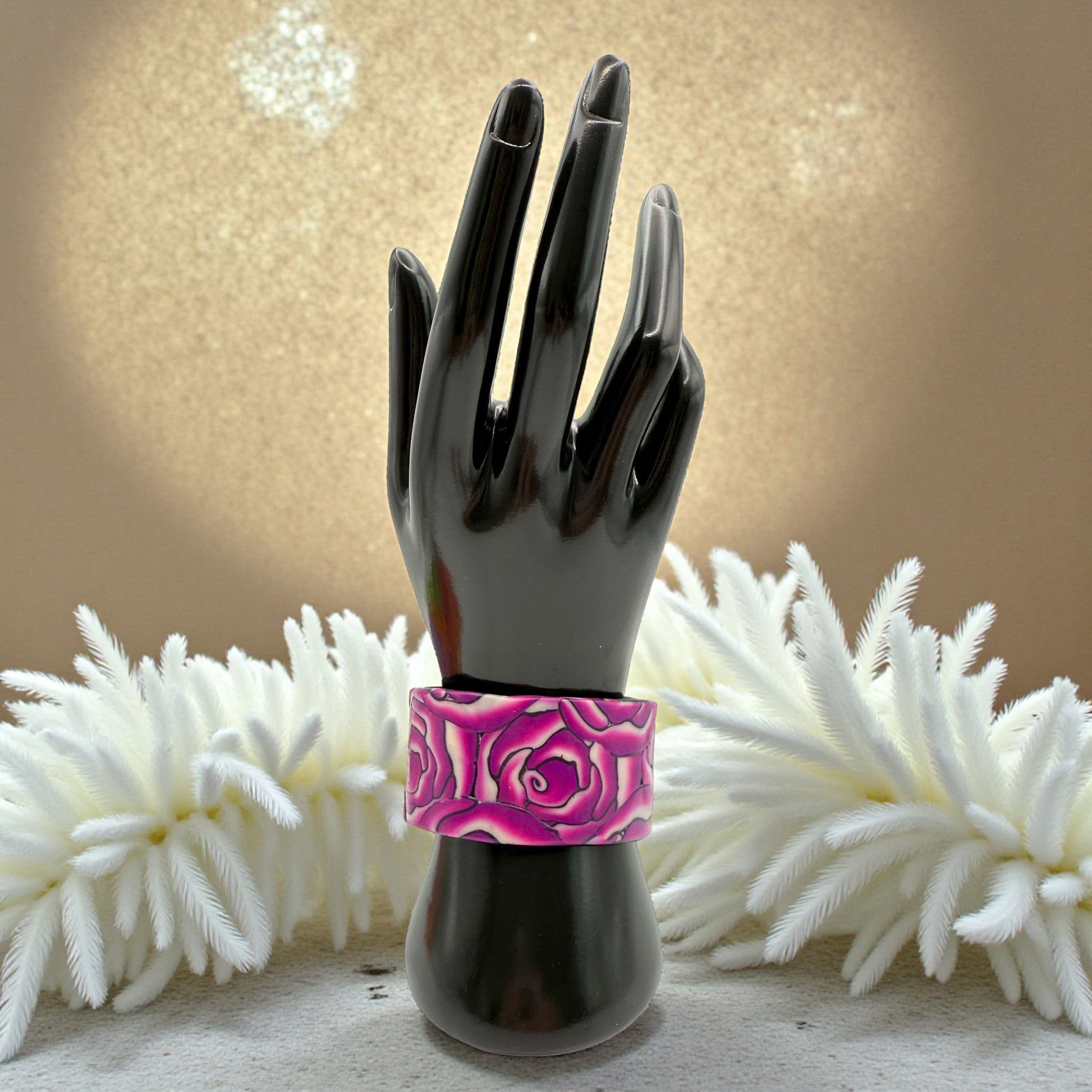 These Pretty Things Cherry Rose Cuff on a black hand mannequin with a cream feather boa in the background
