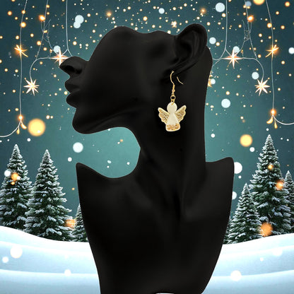 Christmas Angel earrings on a black mannequin against a festive background with trees and lights.