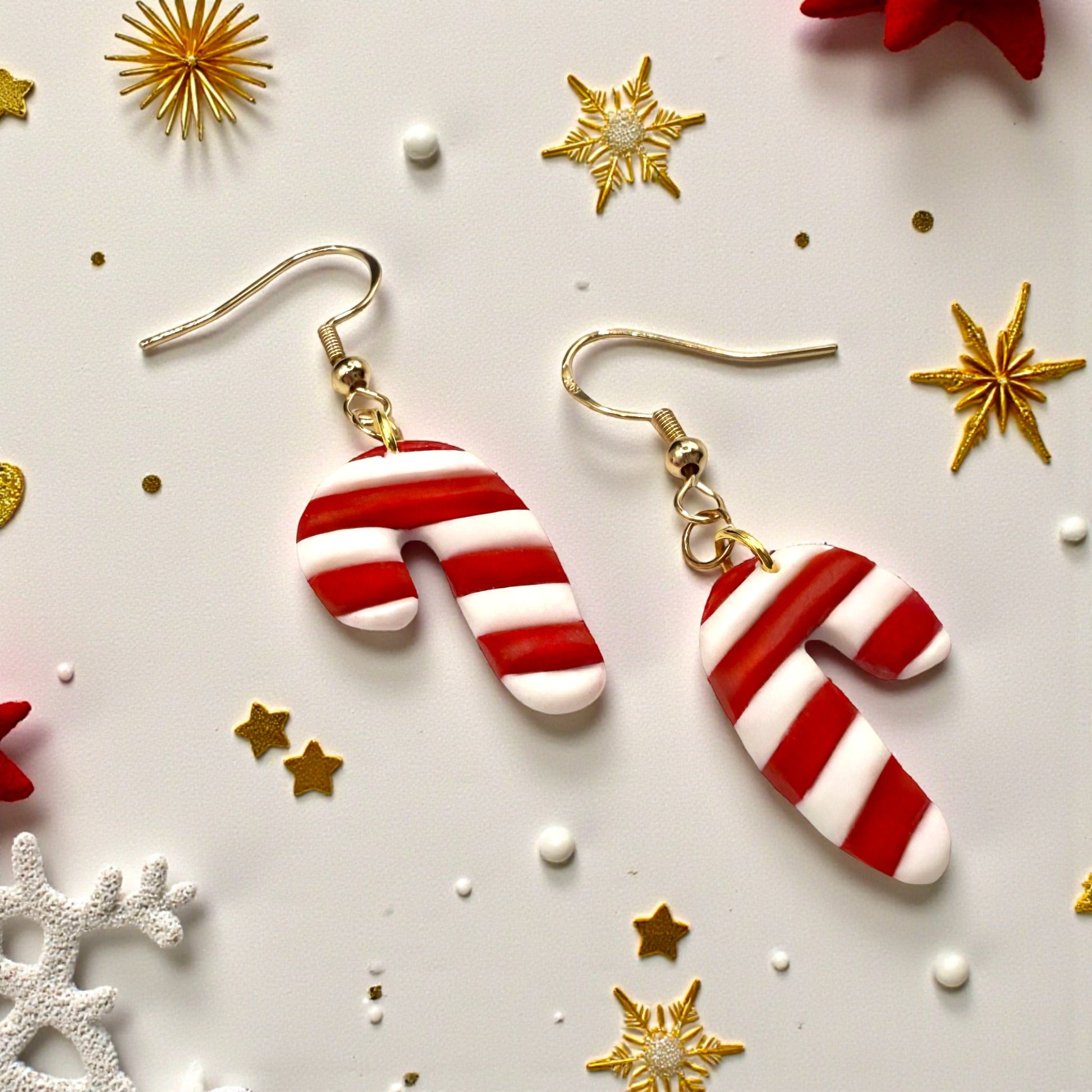 Christmas Candy Cane earrings of red and white with a festive themed background containing gold and red stars with snowflakes.