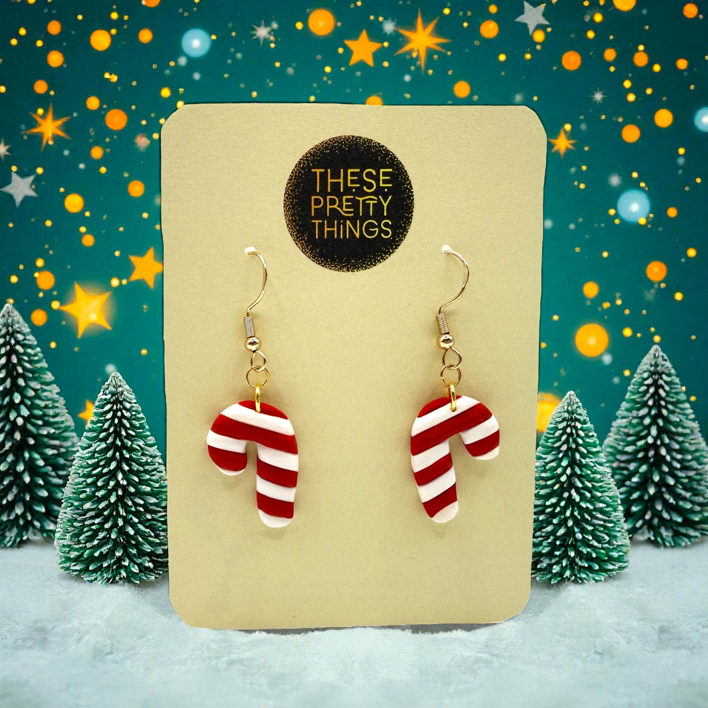 Christmas Candy Cane earrings on a 'These Pretty Things' preesentation card with a festive background showing snow, Christmas trees and stars.