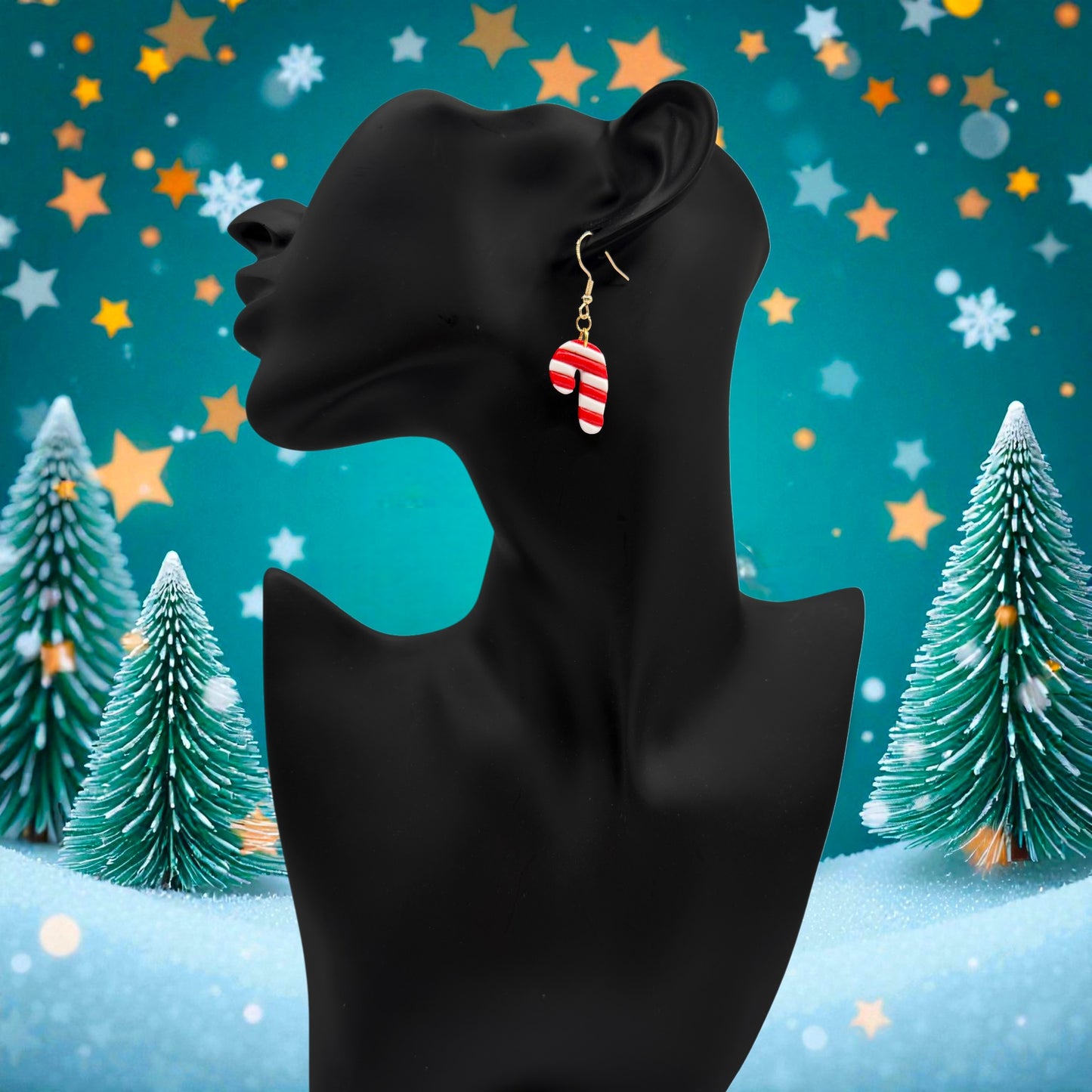 Black mannequin head with Christmas Candy Cane earrings against a festive background with trees and stars.