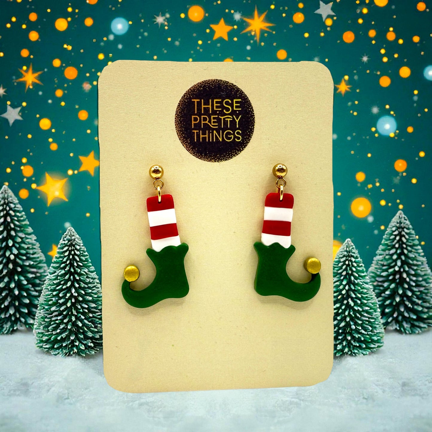 Elf Boots & Socis earrings on a 'These Pretty Things' presentation card with a festive background including snow, Christmas trees and stars.