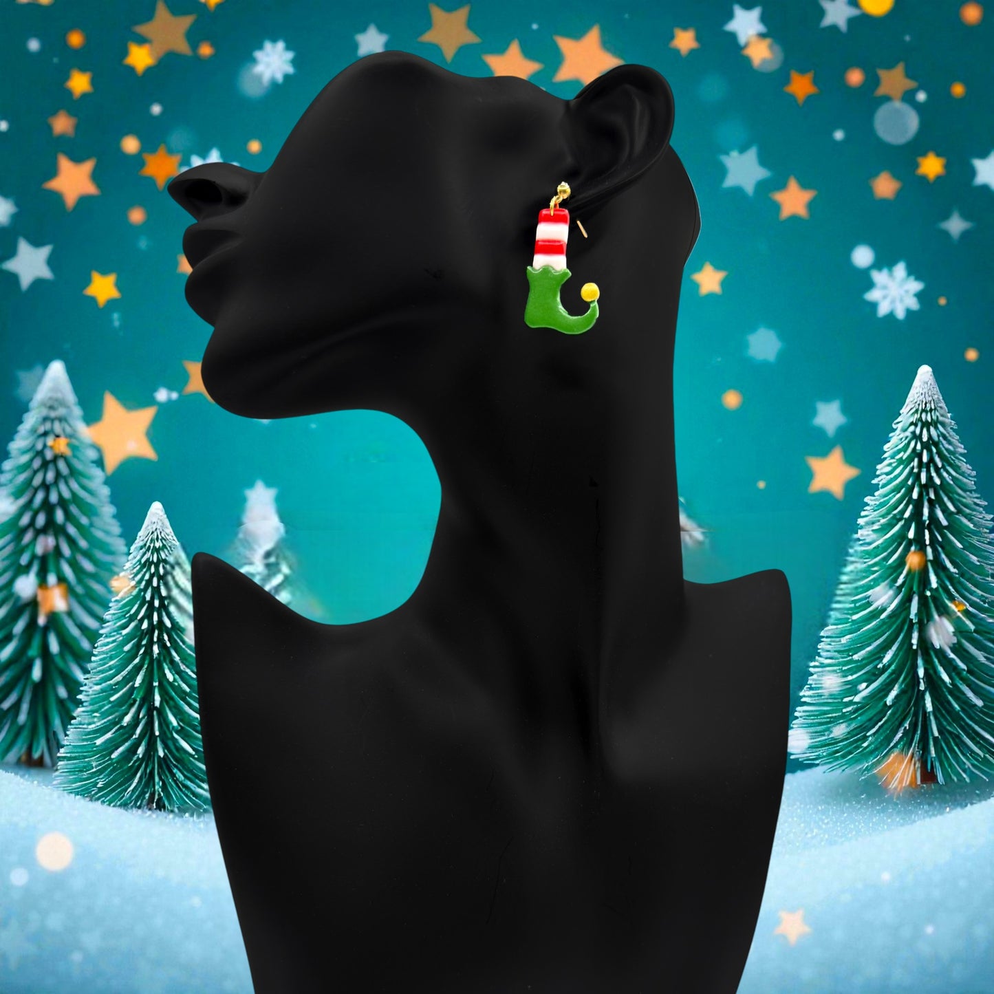 Elf Boots & Socks earrings on a black mannequin against a festive background with Christmas trees and stars.