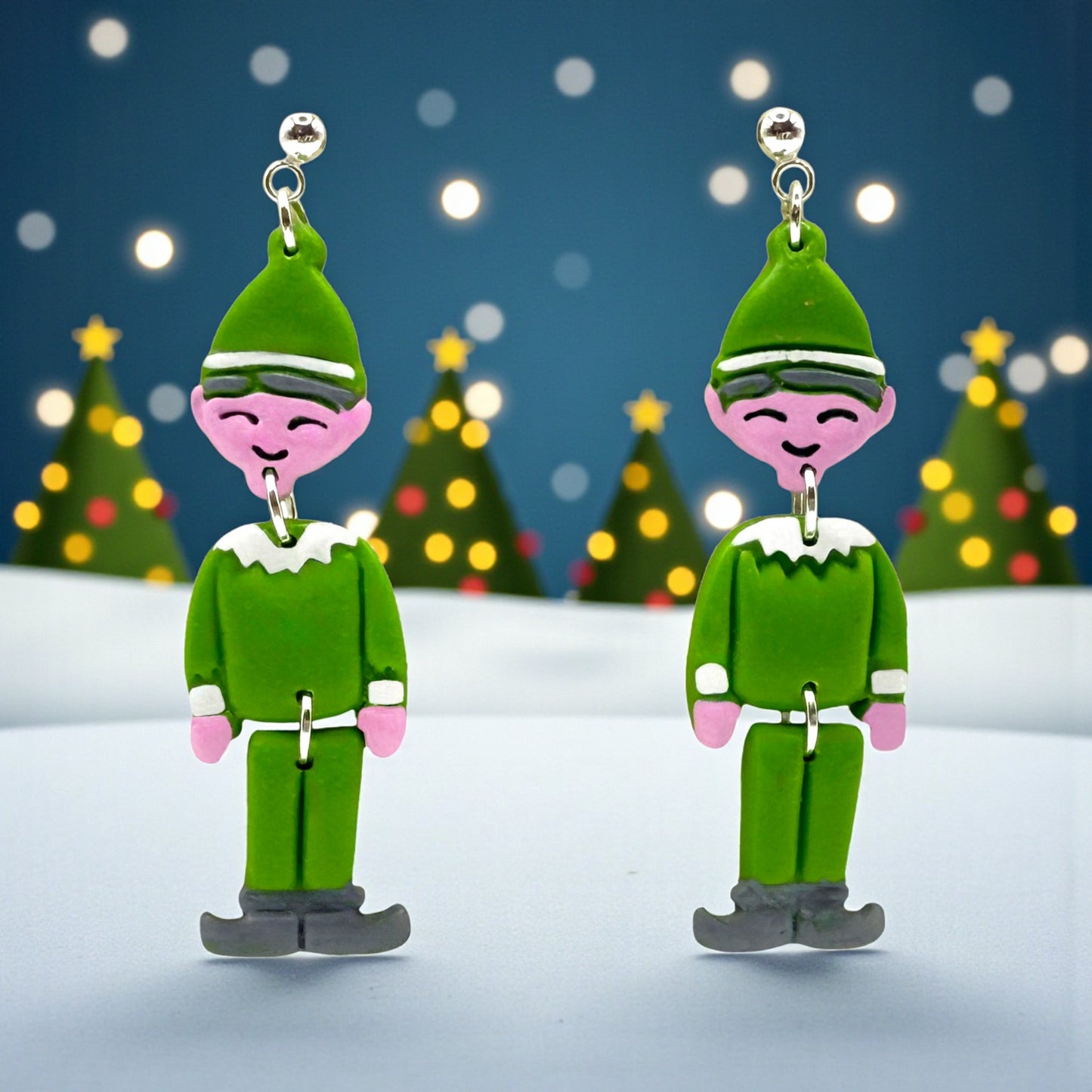 Elf earrings with a festive background of Christmas trees and lights.