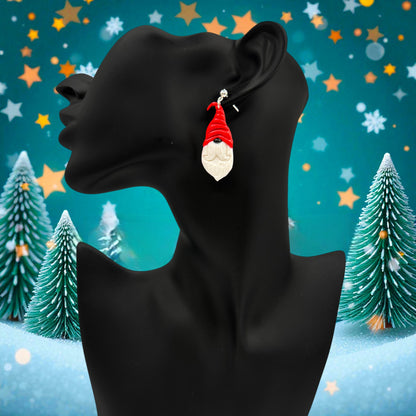 Nordic Santa earrings from These Pretty Things on a black mannequin with a festive background including Christmas trees, stars and snow.