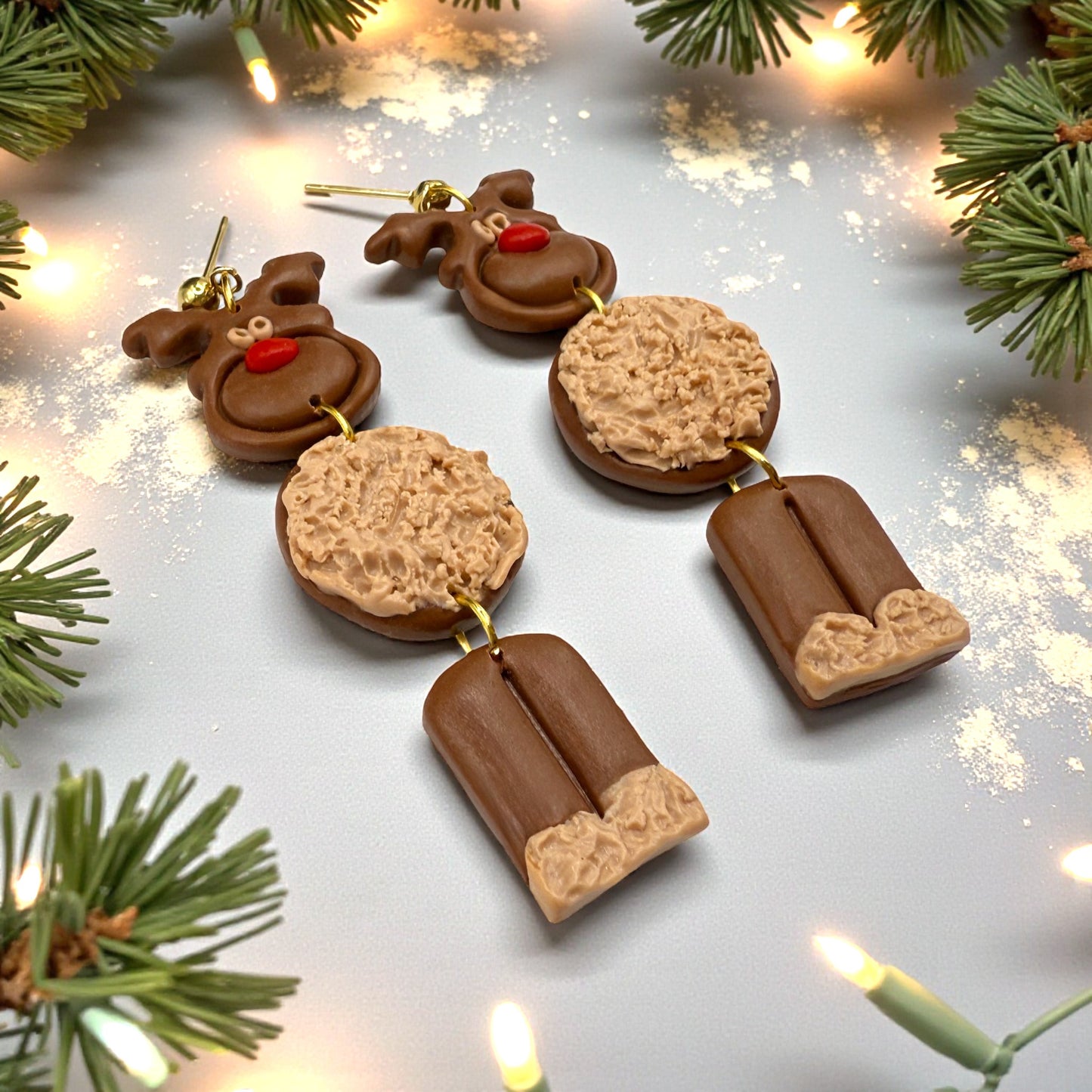 Christmas Reindeer earrings on a festive background with snow and pine branches
