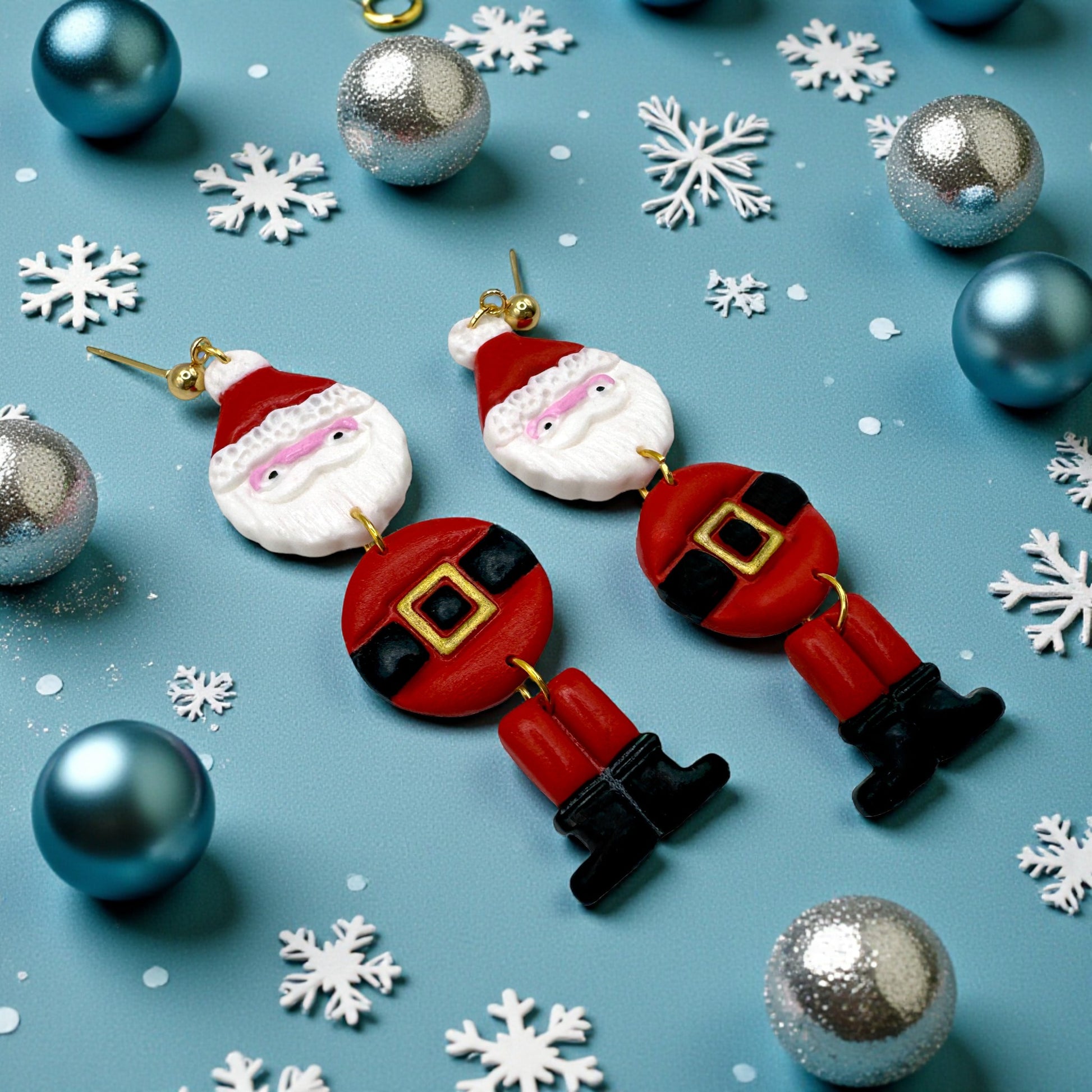 Santa Claus earrings on a blue background with Christmas ornaments and snowflakes.