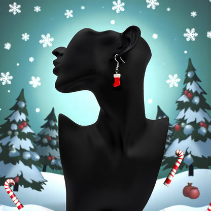 A black mannequin head with Christmas Stocking earrings in red and white against a festive background with trees and snowflakes.
