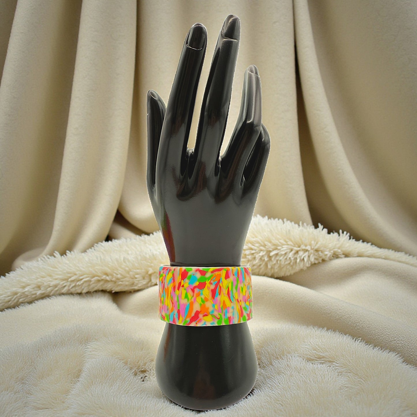 These Pretty Things Confetti Cuff on a black hand mannequin with a cream fur blanket and cream curtian in the background