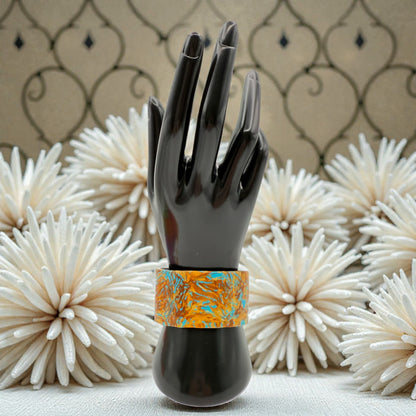 These Pretty Things Fire & Ice Cuff on a black hand mannequin with a cream feather boa in the background.