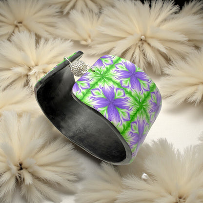 These Pretty Things Fleur De Lys Cuff with a background of a white feather boa