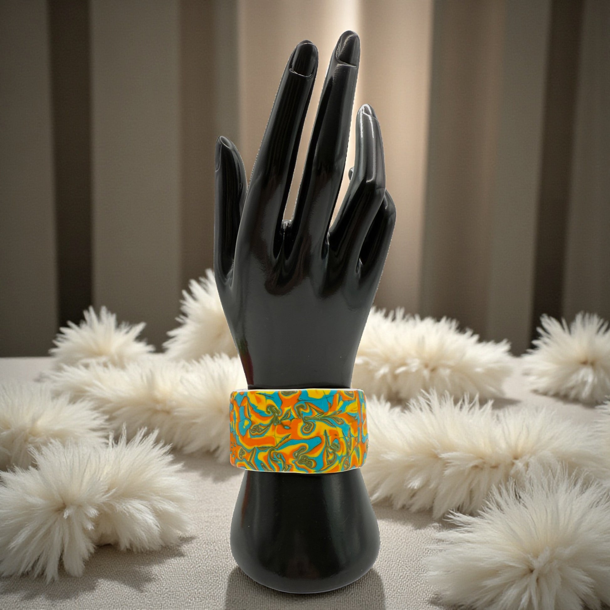 These Pretty Things Hawaiian Dream Cuff on a black hand mannequin with a white feather boa in the background.