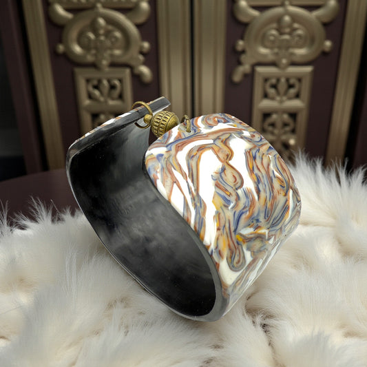 These Pretty Things Marbled Earth Cuff set in a beige feather boa on a wood table