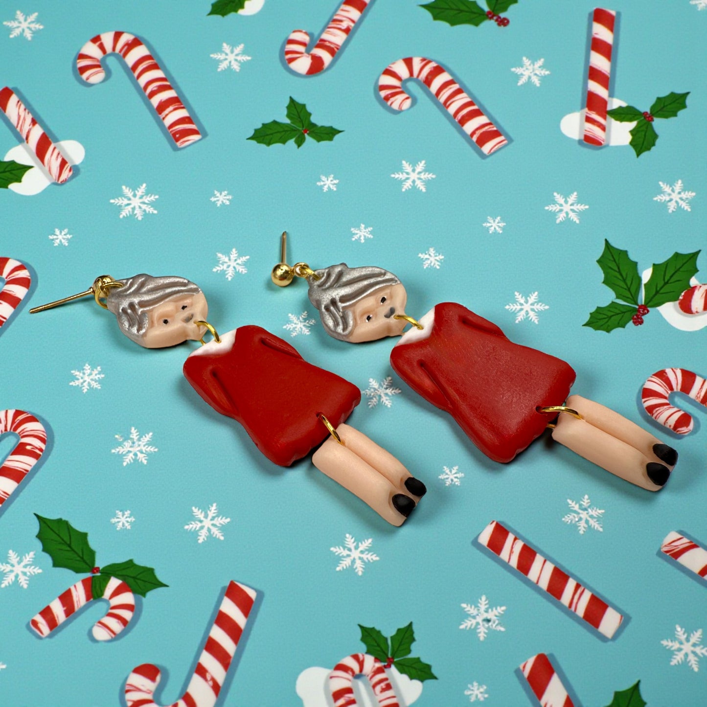 Festive Mrs Christmas earrings on a Christmas-themed background with candy canes and holly.