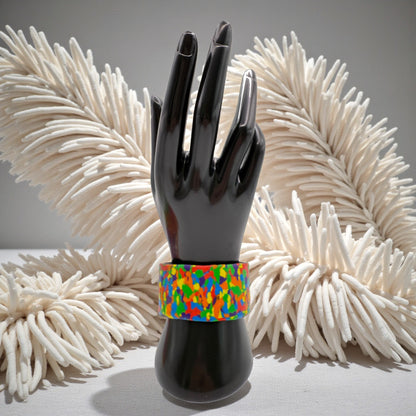 These Pretty Things Pixel Party Cuff on a black hand mannequin with a beige feather boa in the background