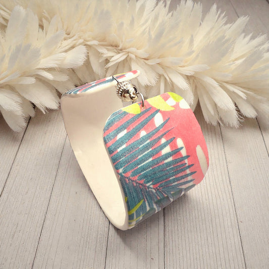 These Pretty Things Rainbow Forest Cuff on a table with a creamy white feather boa in the background