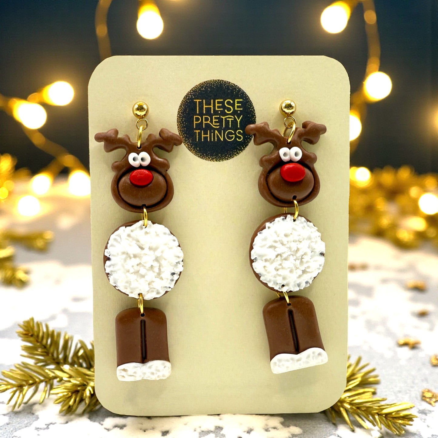 Dark brown Reindeer earrings on a presentation card with 'These Pretty Things' branding, against a festive background.