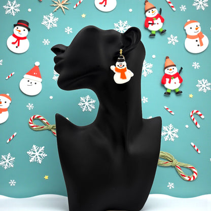 Snowman earring on a black mannequin against a Christmas-themed blue background with snowflakes, candy canes, and snowmen.