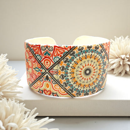 These Pretty Things Jaipur Cuff sat on a beige colour platform with beige flowers around it
